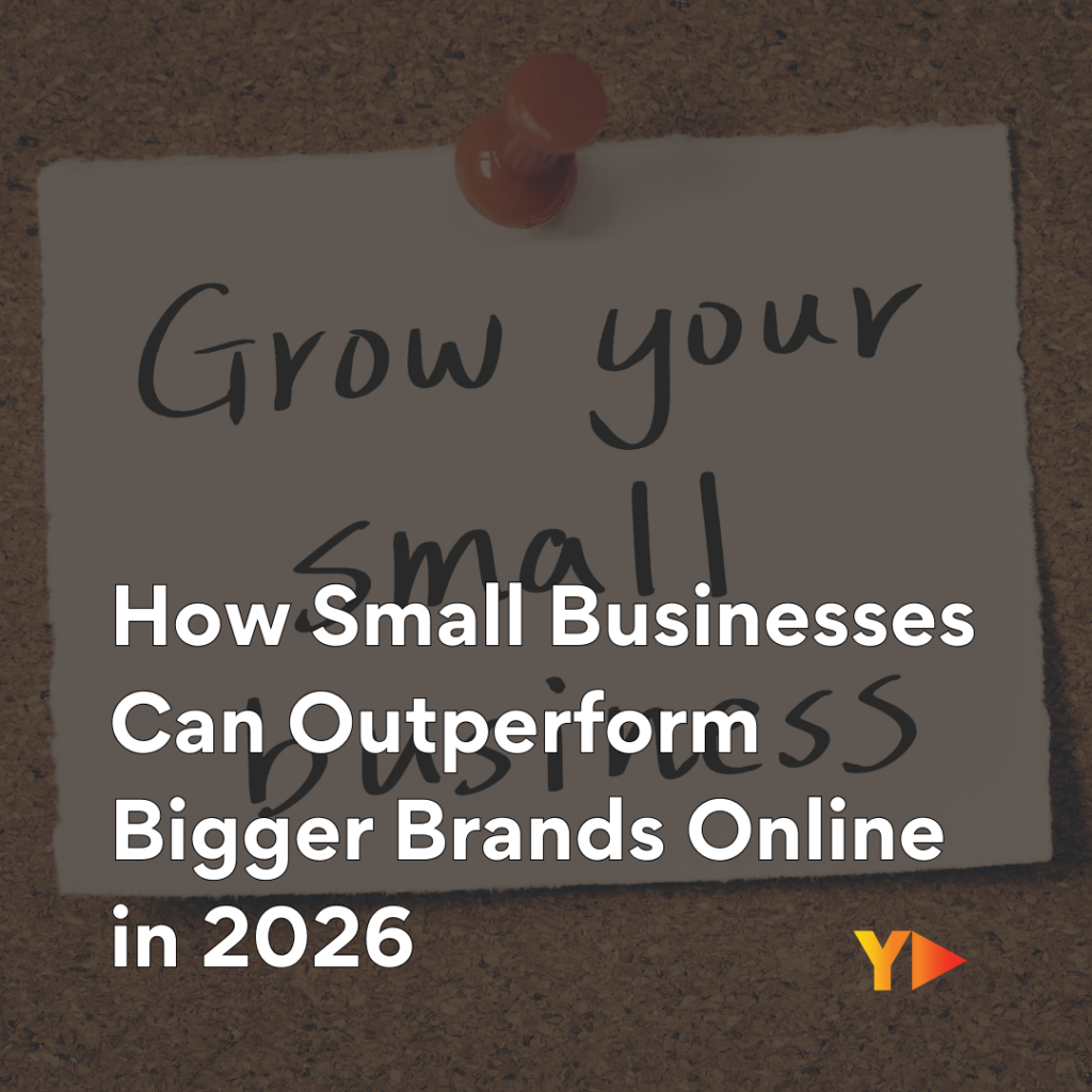 A square image featuring a cork board background with a white paper note pinned to it by a single orange-red pin. Hand-written on the note in dark gray marker is "Grow your small business." Pinned over this text is a prominent semi-transparent dark gray box with white text that reads: "How Small Businesses Can Outperform Bigger Brands Online in 2026." The "Y" logo with a play button is in the bottom right corner.